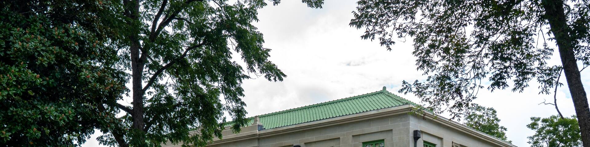 A large, historic building with green-framed windows and a green roof.