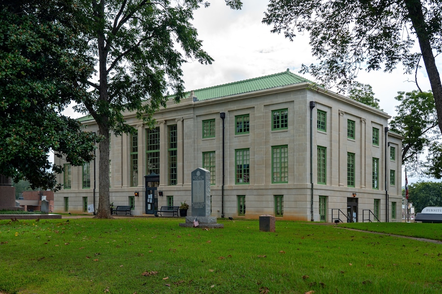A large, historic building with green-framed windows and a green roof.