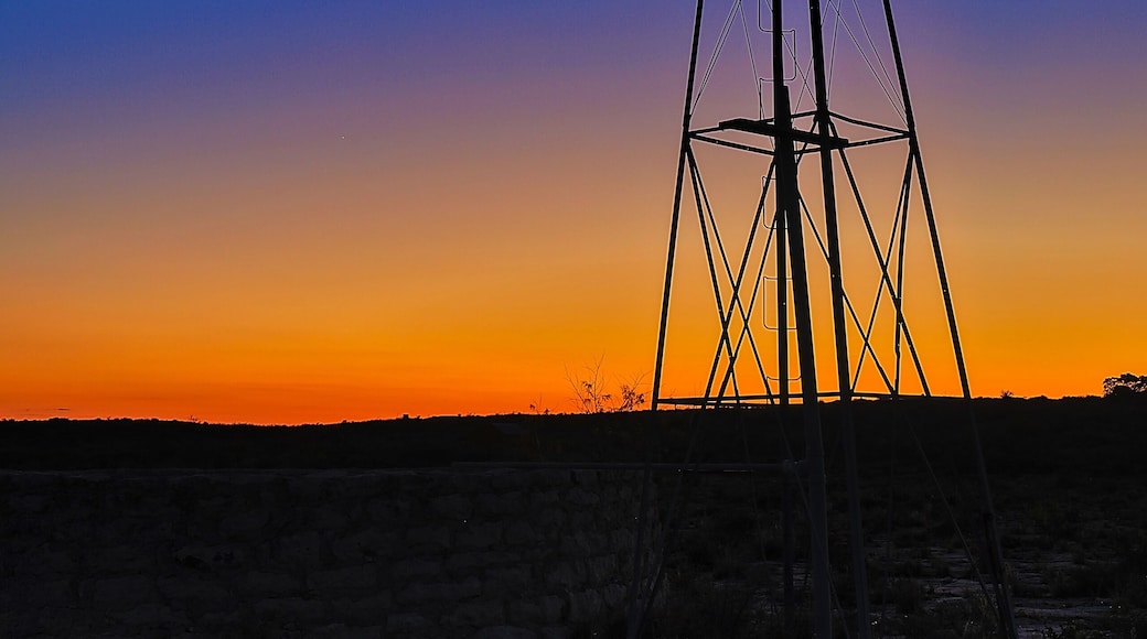 Sunset at Seminole Canyon State Park behind an old windmill and stock tank.