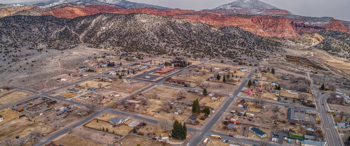 An aerial view of a town with a grid of streets, surrounded by mountains and sparse vegetation.