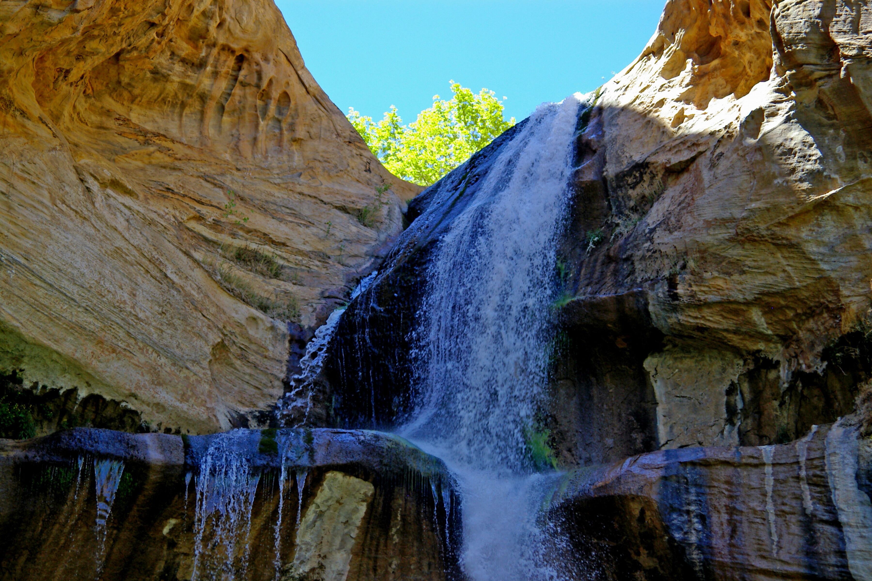 Named for its use as a natural pen for calves back in the late 1800’s and early 1900’s, the creek remained relatively unknown as a tourist destination until the formation of the Grand Staircase-Escalante National Monument, under the Clinton administration. Walking between mineral-streaked cliffs of Navajo Sandstone, hikers pass beaver ponds and pre-historic rock art sites en route to the paradisiacal pools.

Trail Head: 37.794049, -111.414733
Trail Type: Hiking
Length: 5.84 roundtrip
Difficulty: Moderate

The trailhead is located at the Calf Creek Campground on Highway 12, 11 miles south of the town of Boulder, and 15 miles east of the town of Escalante. The highway follows the route of the creek for most of the distance, atop the bluff to the east of the canyon.