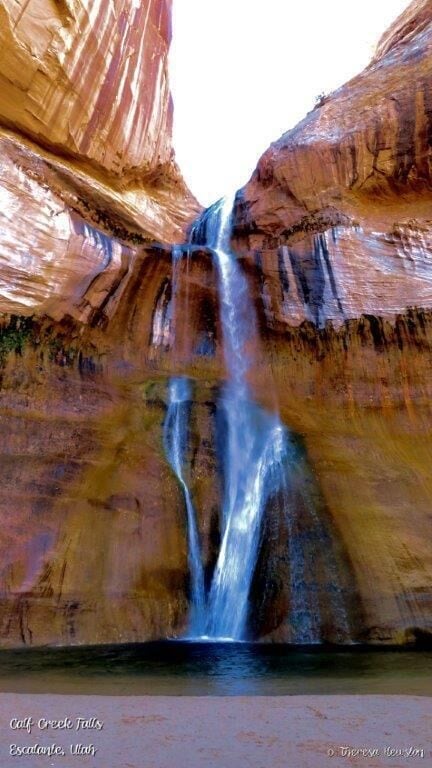 A waterfall in a canyon with red rock walls.