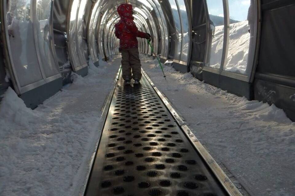 A snow-covered tunnel with a person in a red jacket walking through.