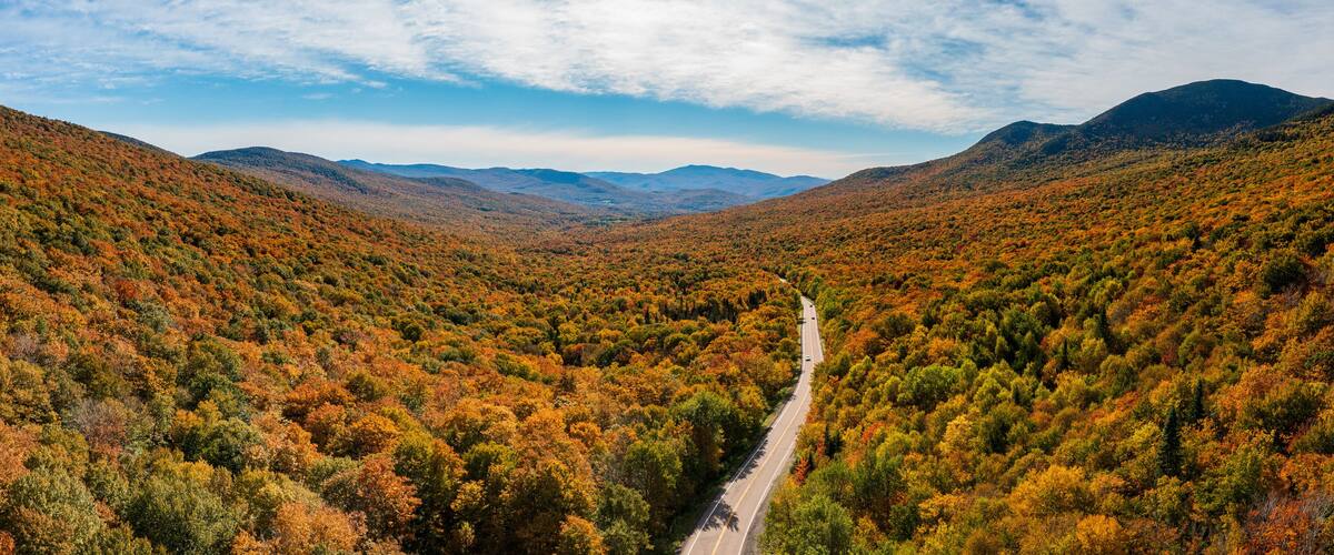 A road through a forested valley with autumn foliage.