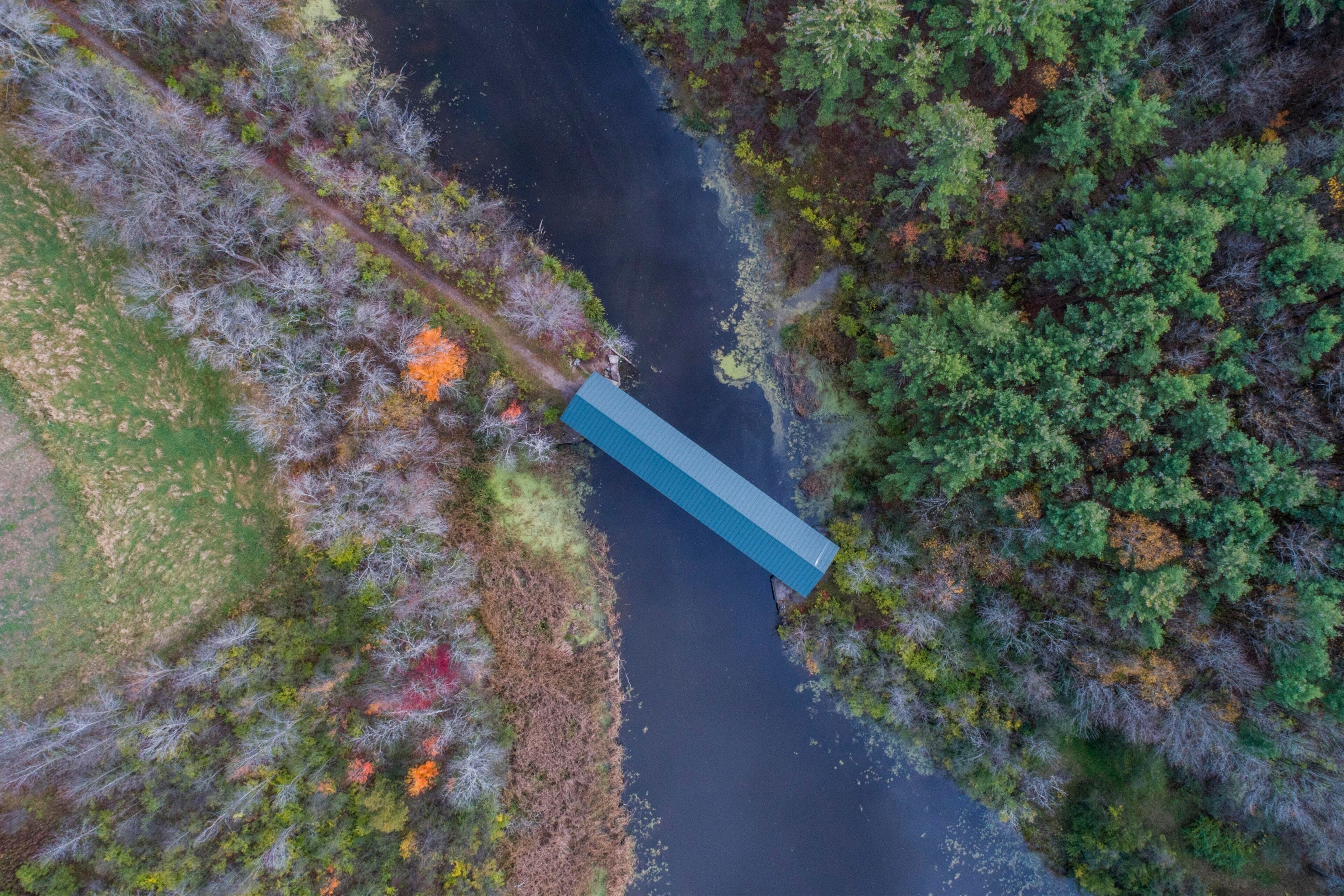 An aerial view of a river with a bridge and surrounding forest.
