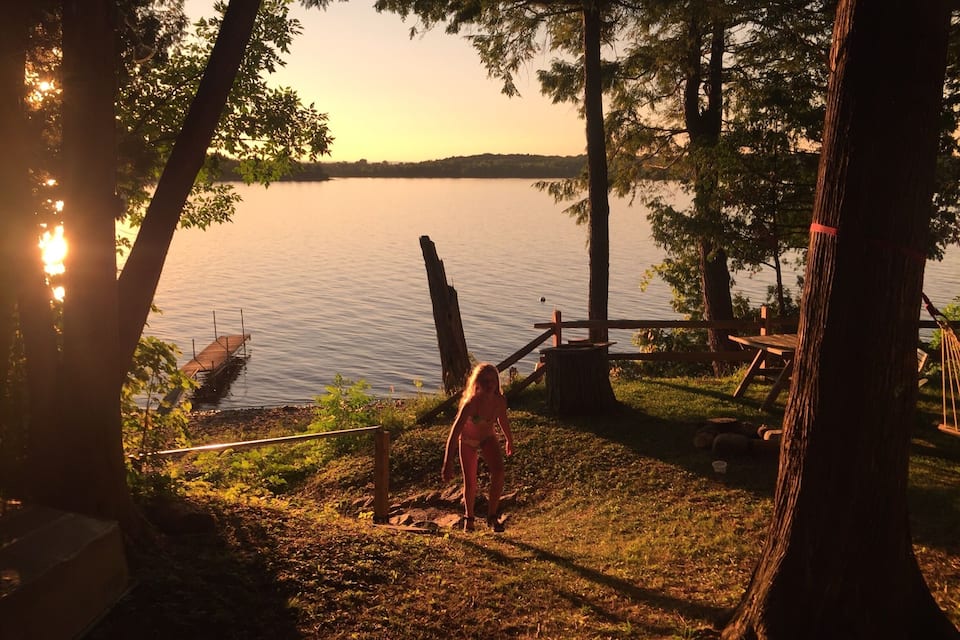 A lakeside scene with a wooden dock, trees, and a picnic area.