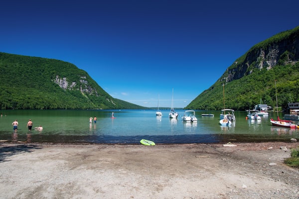 A lake surrounded by mountains with boats and people on the shore.