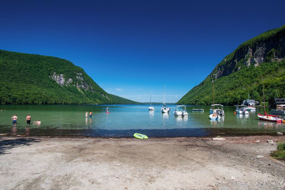 Um lago rodeado por montanhas, com barcos e pessoas na margem.