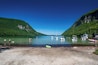 A lake surrounded by mountains with boats and people on the shore.