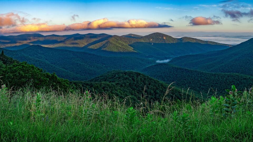 A mountainous landscape with dense forests and a winding road.