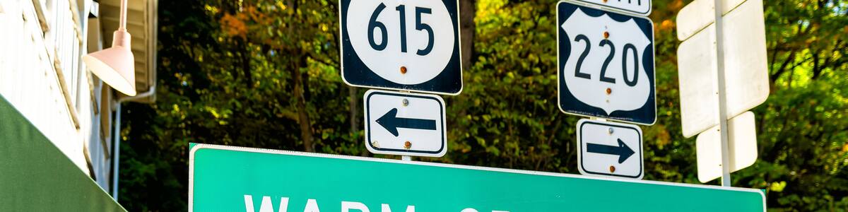 Straßenschilder für die Richtungen 615 und 220 Nord, sowie ein Schild für Warm Springs.