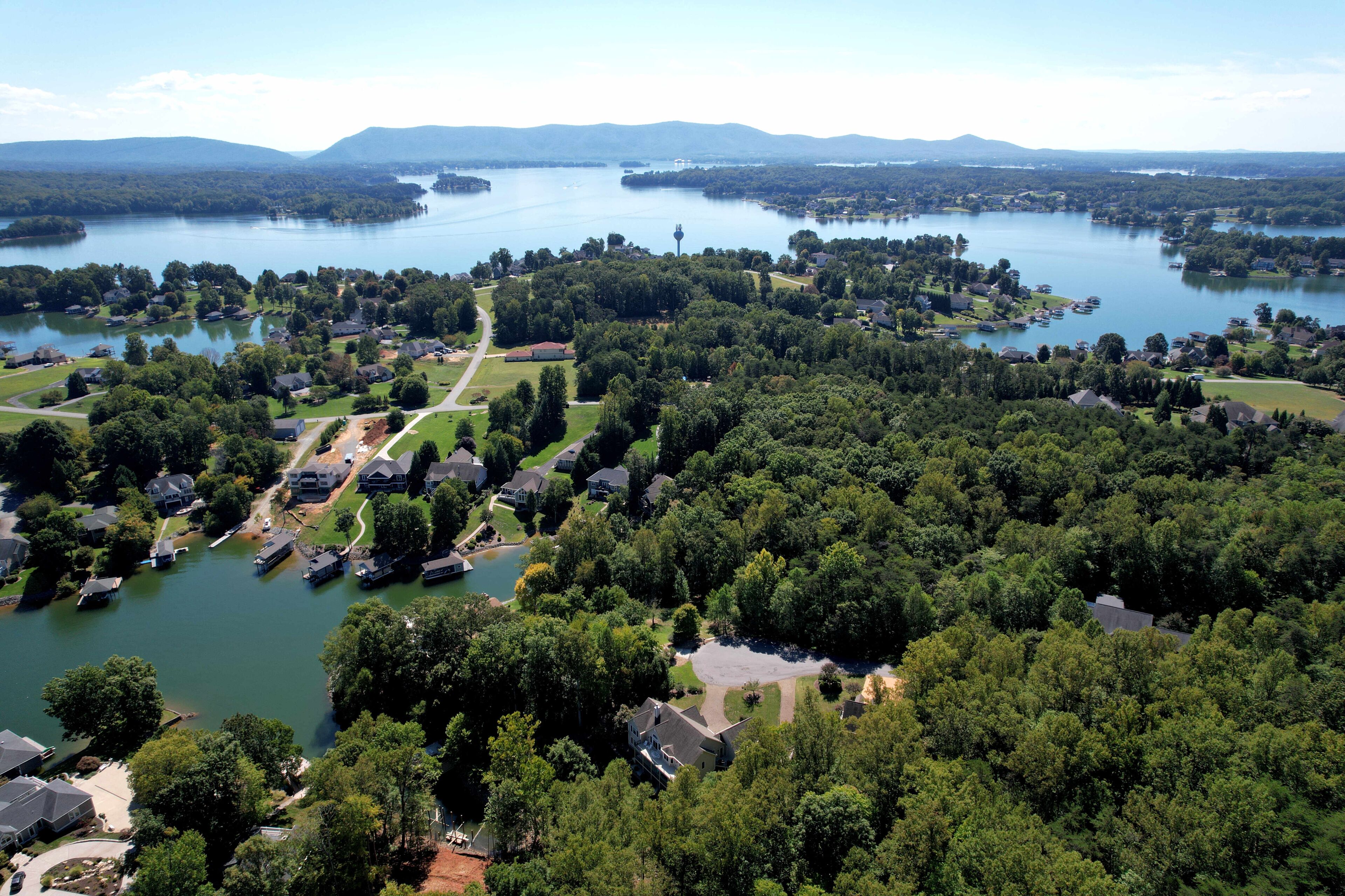A lakeside community with houses, a lighthouse, and surrounding greenery.