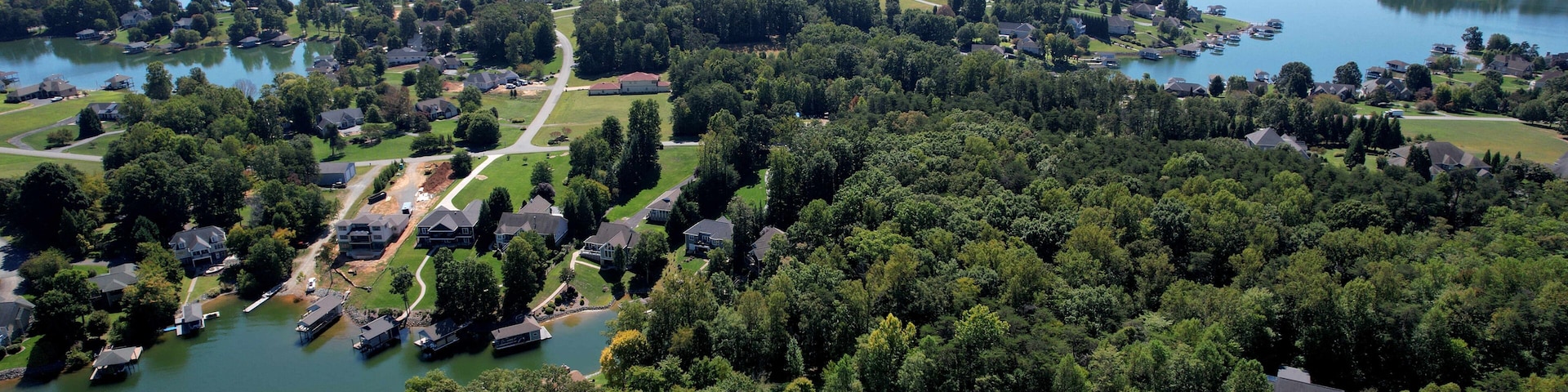 A lakeside community with houses, a lighthouse, and surrounding greenery.