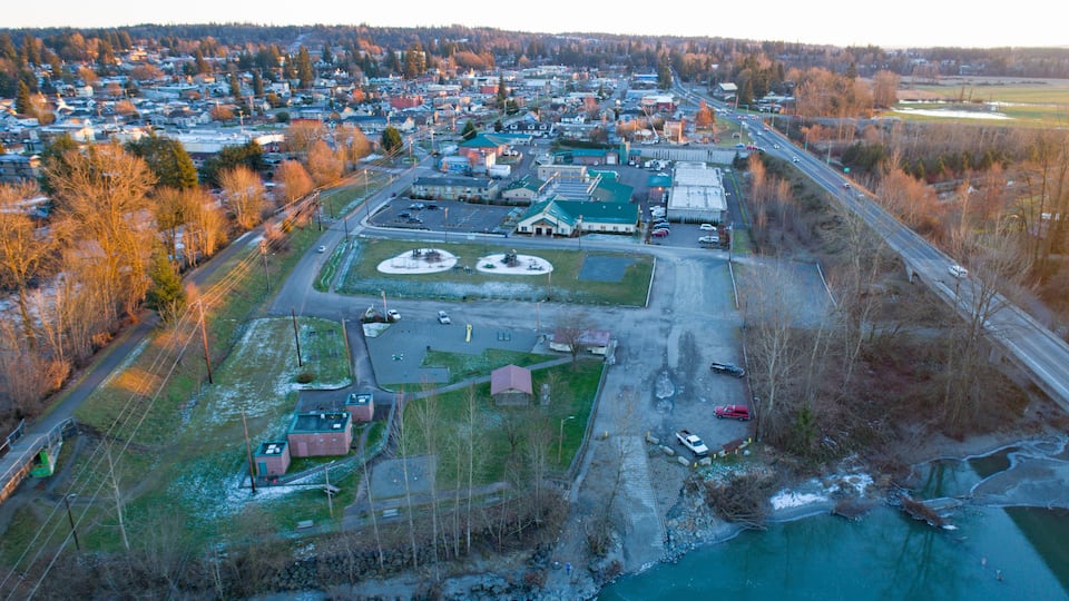 An aerial view of a town with a river, a large parking lot, and several buildings.