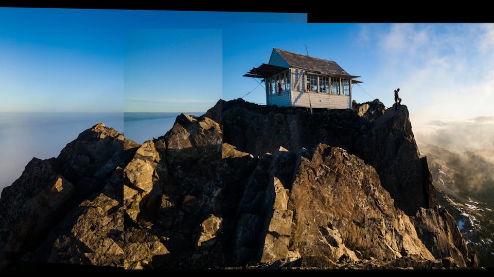 Hiker stands at sunrise outside Three Fingers Lookout, North Cascades