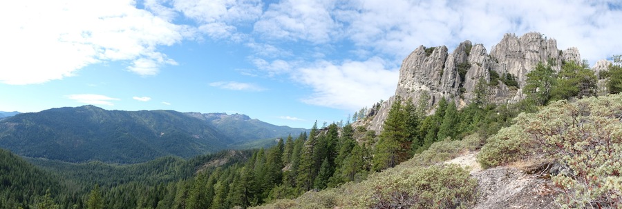 A mountainous landscape with dense forests and rocky cliffs.