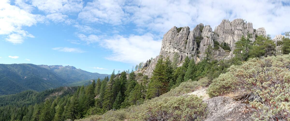A mountainous landscape with dense forests and rocky cliffs.