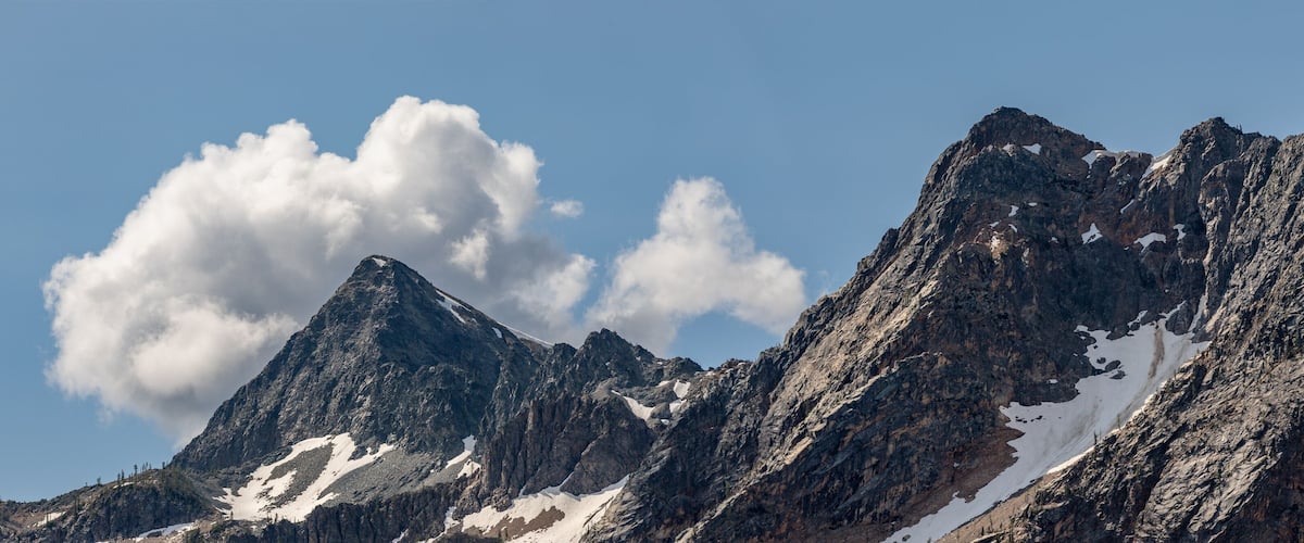 Rugged mountains with snow patches and a prominent cloud formation.