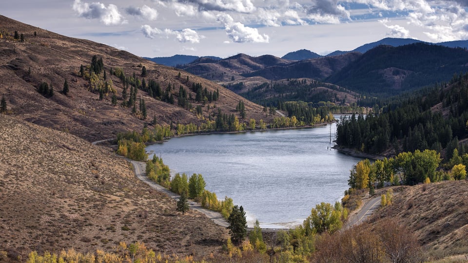 A lake surrounded by hills and autumn-colored trees.