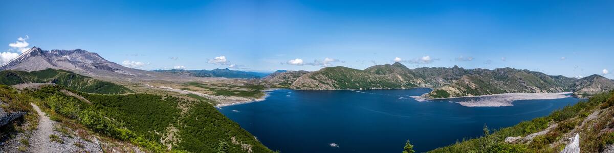 A mountainous landscape with a clear blue lake surrounded by rugged terrain and sparse vegetation.