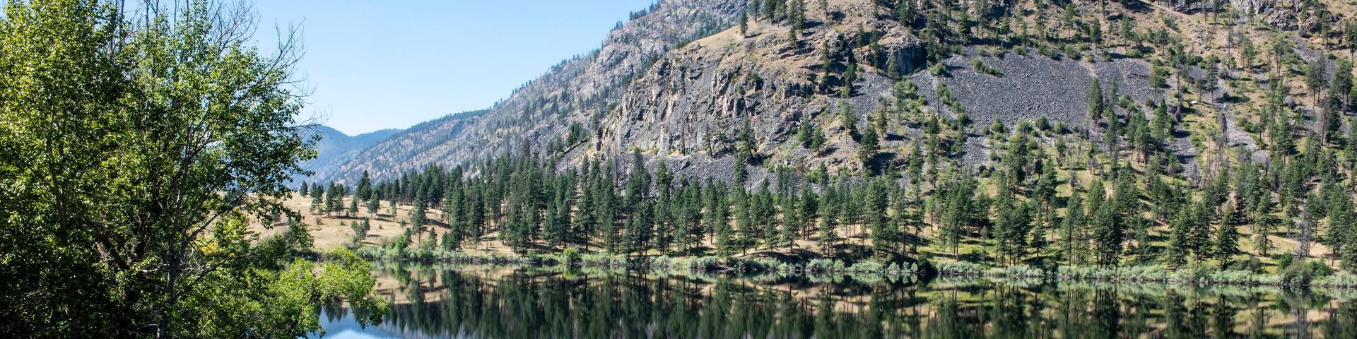 Mountain scene reflected on the pristine Blue Lake in Eastern Washington at the Sinlahekin Wildlife Area near Tonasket; Tonasket, Okanogan County, Washington, United States of America