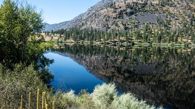 Mountain scene reflected on the pristine Blue Lake in Eastern Washington at the Sinlahekin Wildlife Area near Tonasket; Tonasket, Okanogan County, Washington, United States of America