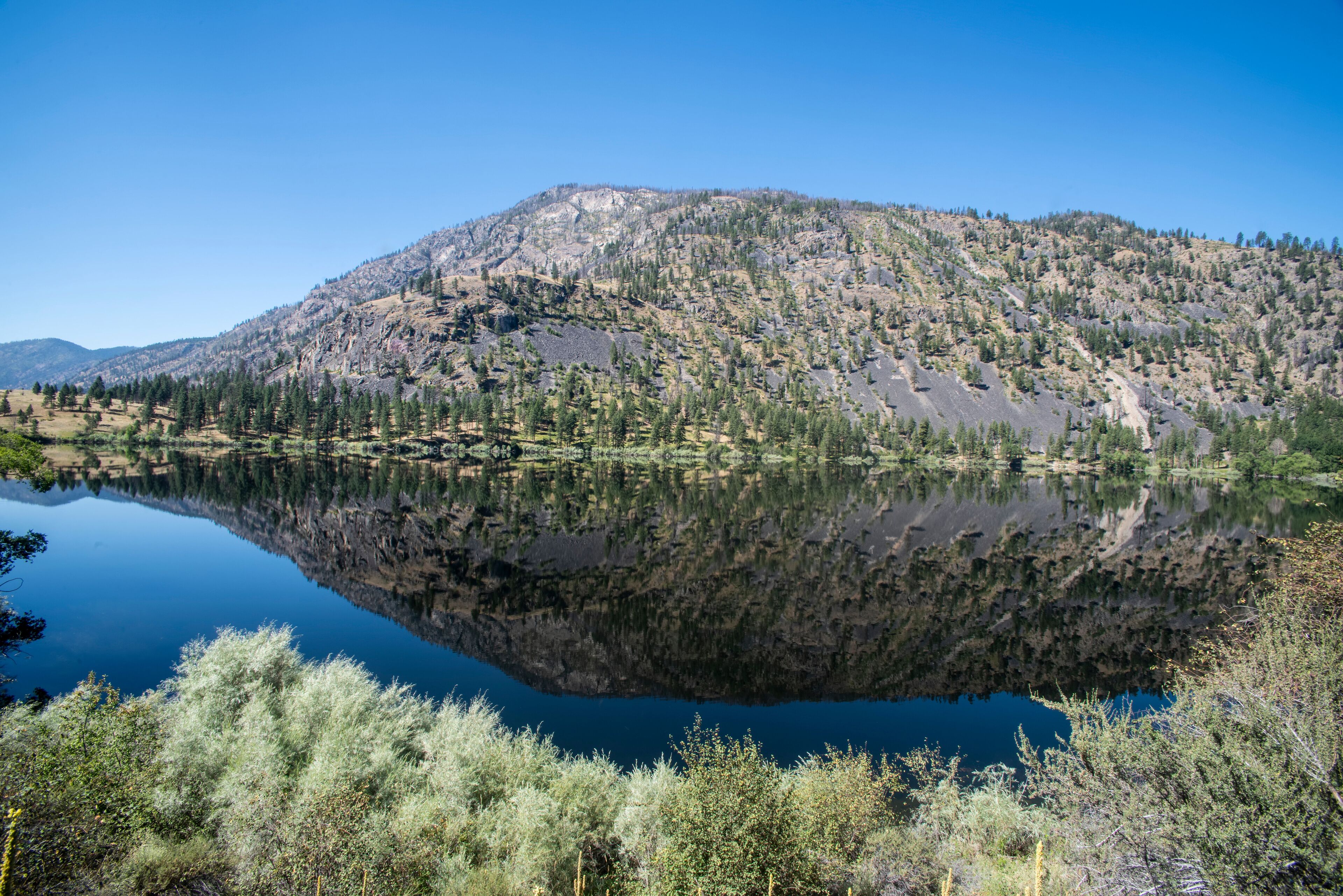 Mountain scene reflected on the pristine Blue Lake in Eastern Washington at the Sinlahekin Wildlife Area near Tonasket; Tonasket, Okanogan County, Washington, United States of America