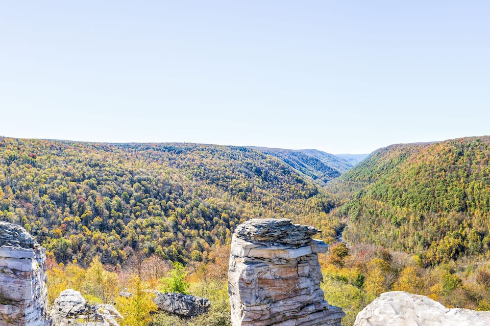 A mountainous landscape with autumn-colored trees and rock formations.