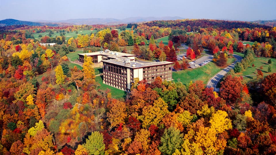 An aerial view of a building surrounded by autumn-colored trees.