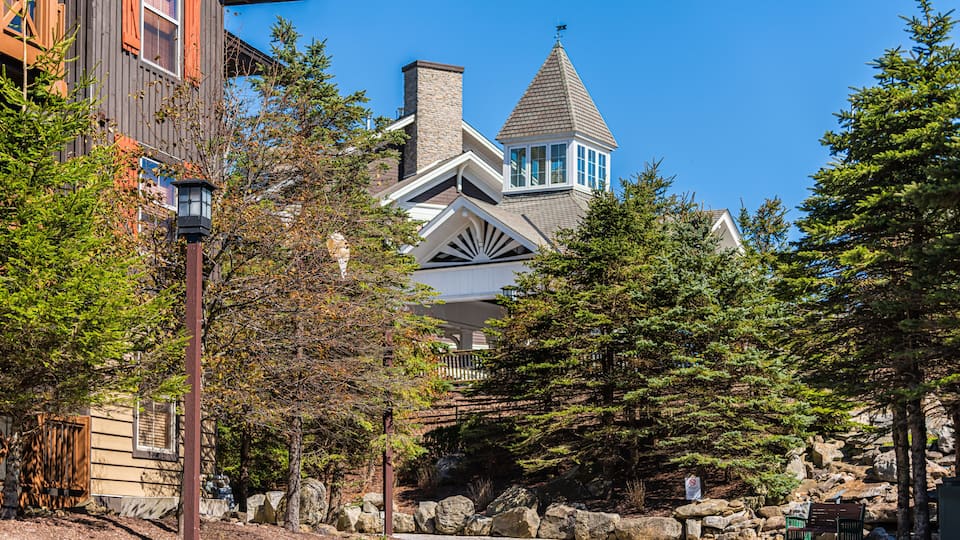 A wooden building with a stone chimney, a stone pathway, and a bench.