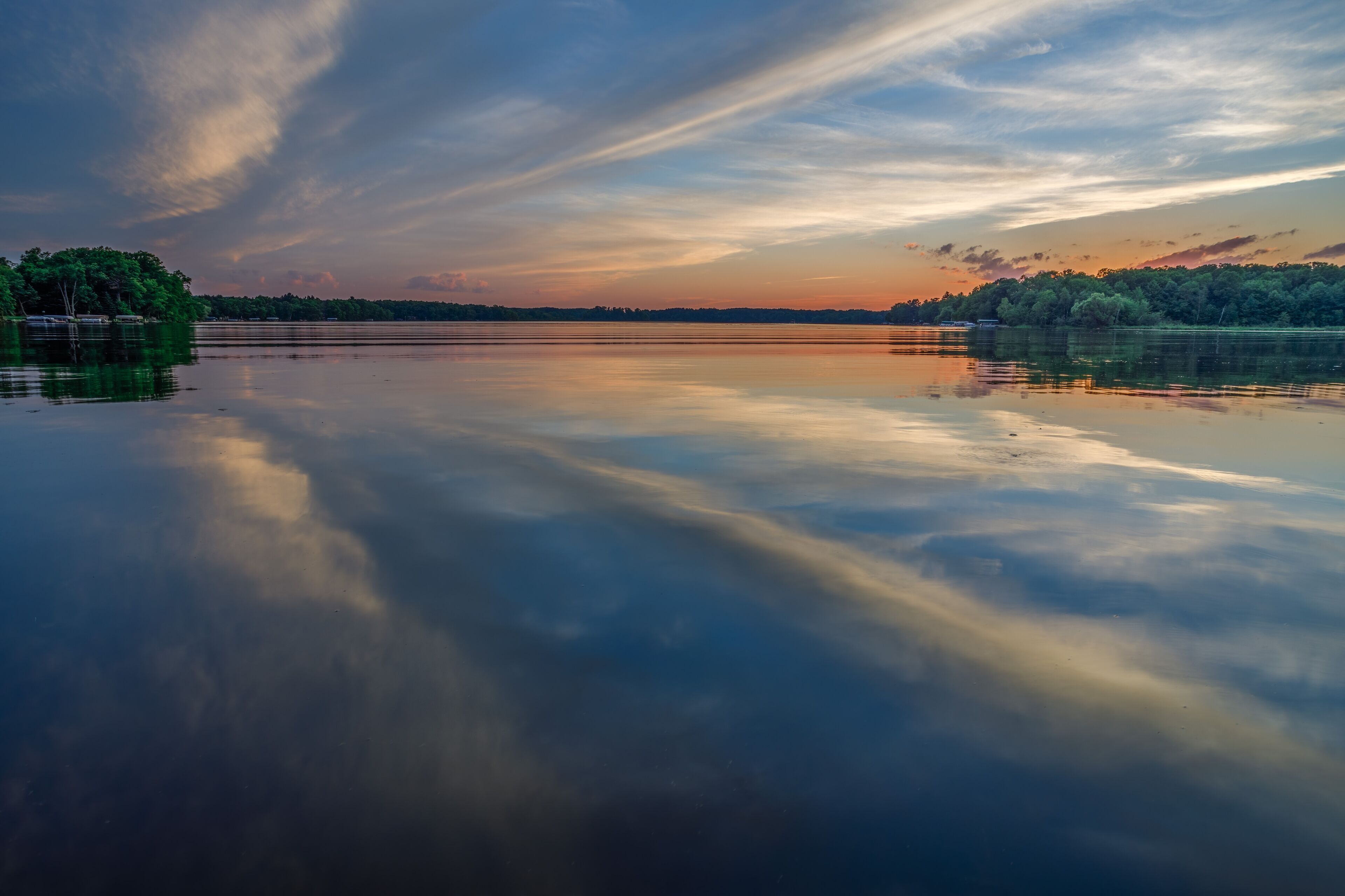 Bright sunset with reflections of clouds on the calm water during summer on Big Moon Lake, Barron County WI
