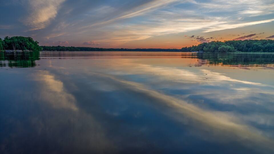 Bright sunset with reflections of clouds on the calm water during summer on Big Moon Lake, Barron County WI