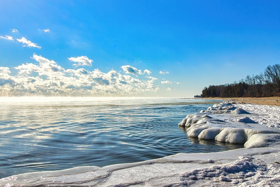 Sunny Winter landscape of a peaceful Lake Michigan with an ice-coated shoreline on a cold day at Harrington Beach State Park, near Belgium, Wisconsin.