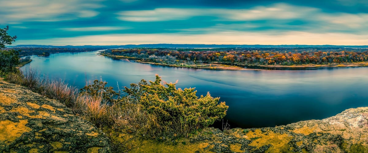 A calm lake surrounded by autumn-colored trees and rocky terrain.
