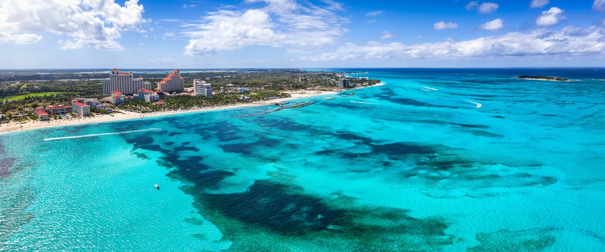 A coastal resort with clear turquoise waters, a beach, and a pier extending into the sea.