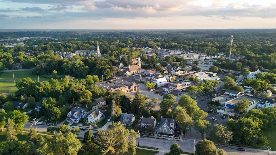 A town with a prominent church steeple, a mix of residential and commercial buildings, and a green park area.