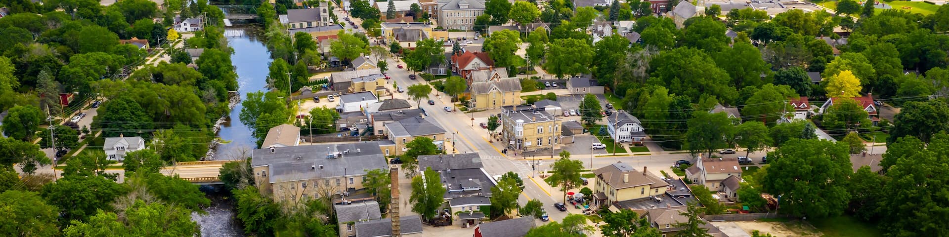 A river flowing through a town with historic buildings and lush greenery.