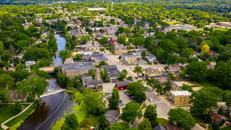 A river flowing through a town with historic buildings and lush greenery.
