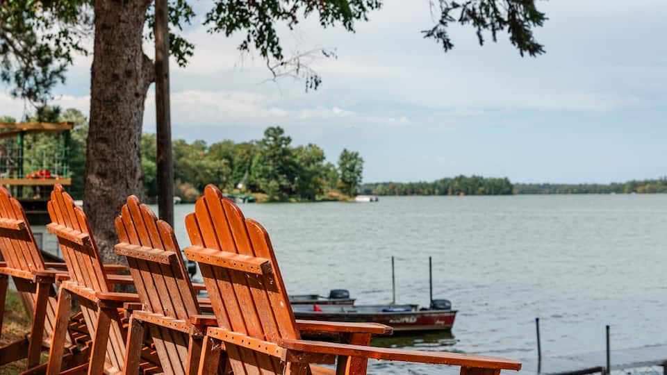 Adirondack chairs facing lake at shoreline