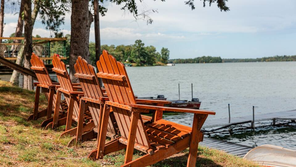 Adirondack chairs facing lake at shoreline