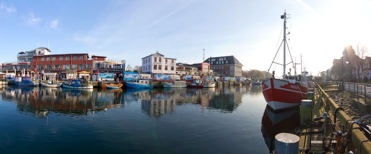 A harbor with boats docked, buildings, and a clear sky.