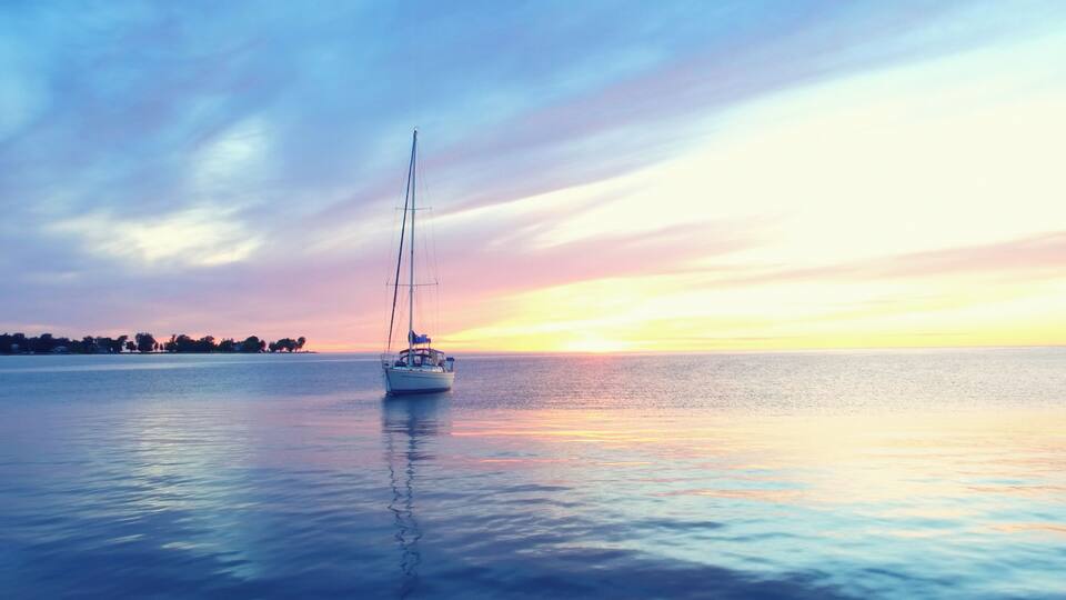 A sailboat on calm waters during sunset.