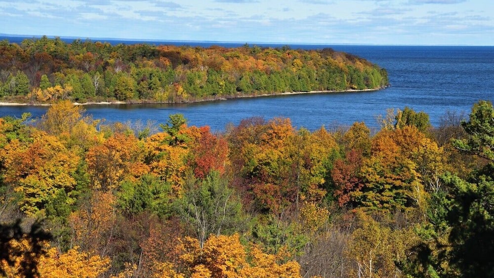 A coastal landscape with autumn foliage and a body of water.