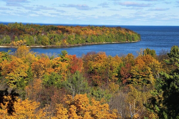 Un paysage côtier aux couleurs automnales, avec un plan d’eau.