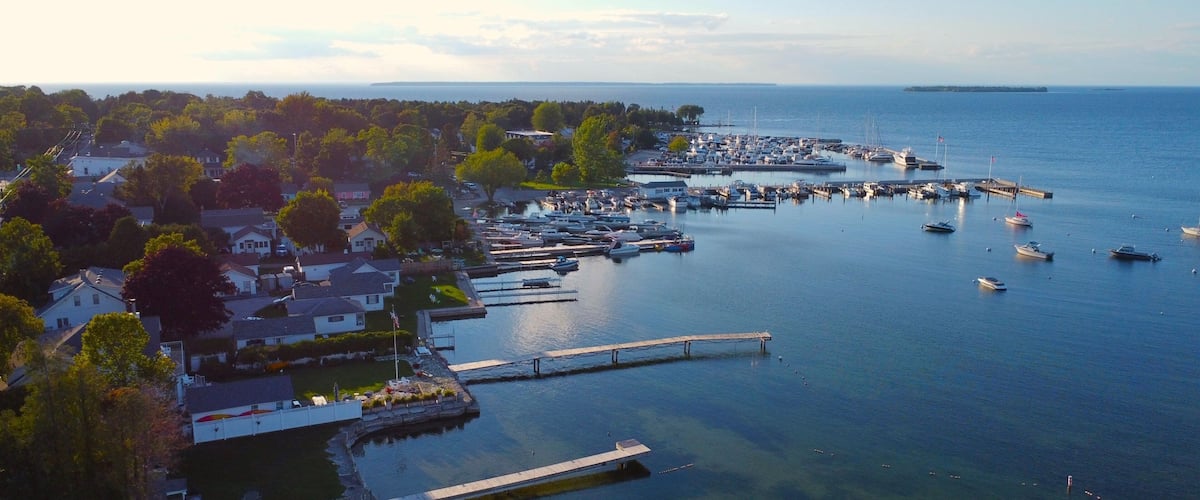A marina with boats, a pier, and residential houses along the waterfront.