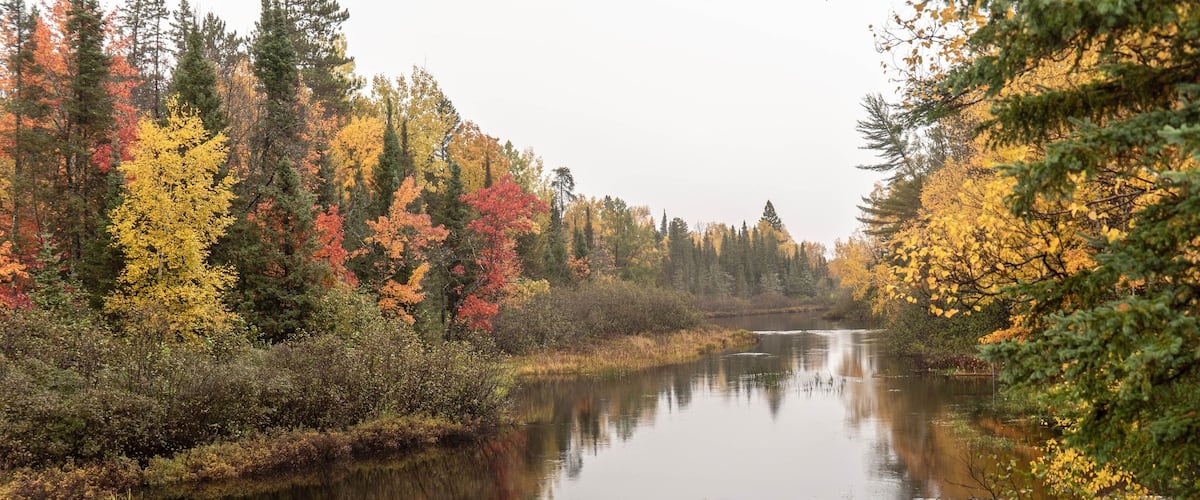 A calm river surrounded by autumn-colored trees.