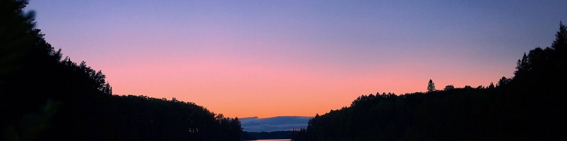 A calm river at dusk with a gradient sky.