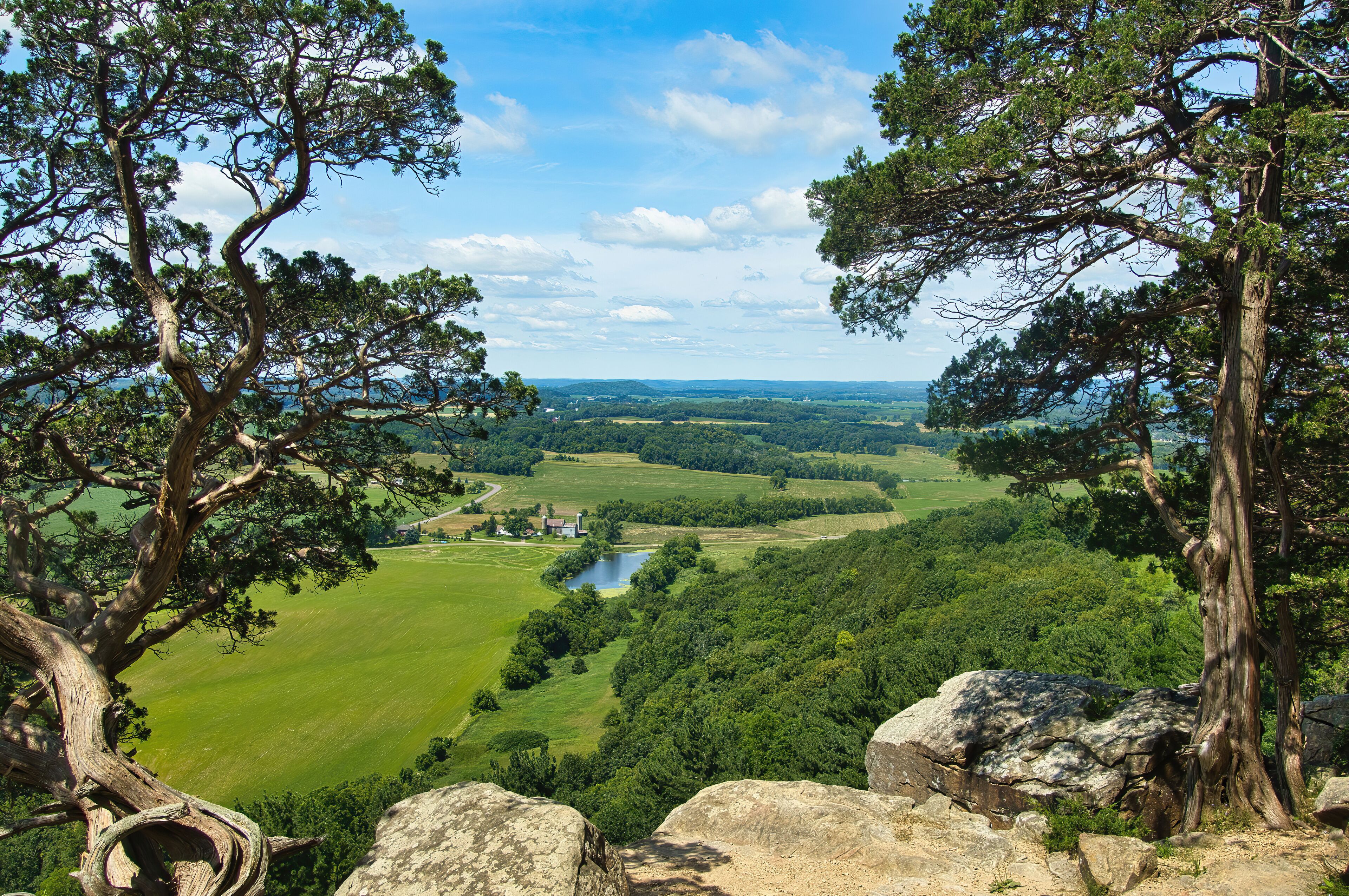 A mountainous landscape with a river, green fields, and a small building.