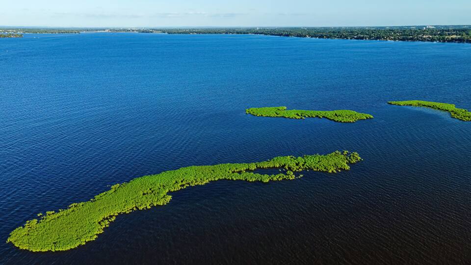 An aerial view of a large body of water with three green islands.