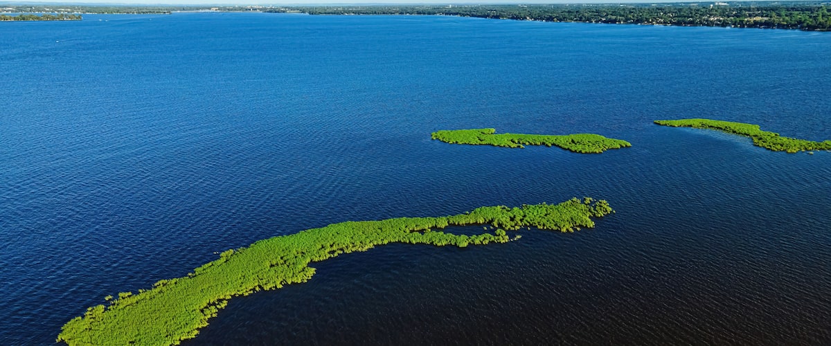 An aerial view of a large body of water with three green islands.